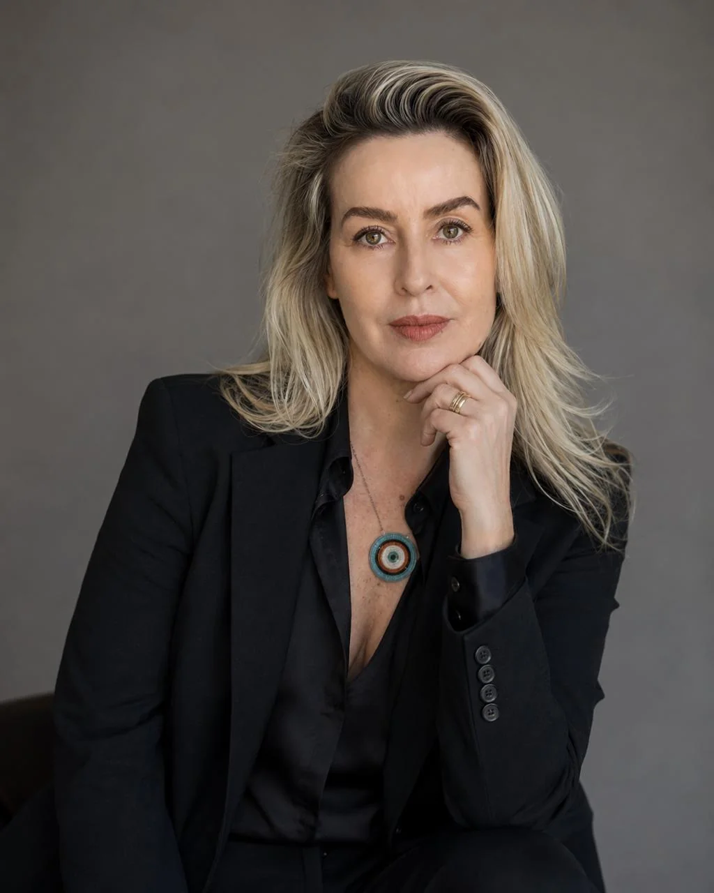 Retrato de Daniella Prestes em terno preto, olhando para a câmera
